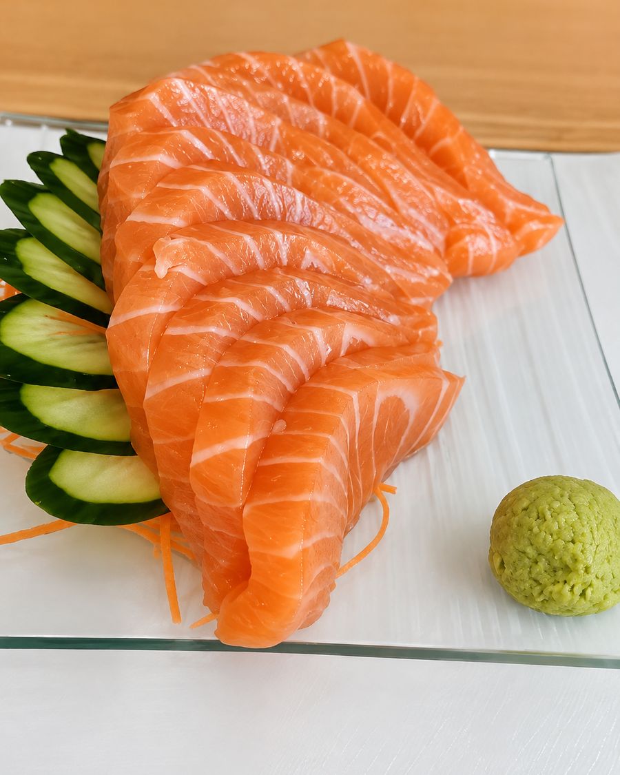 Láminas de sashimi de salmón dispuestas en abanico, con pepino y wasabi.